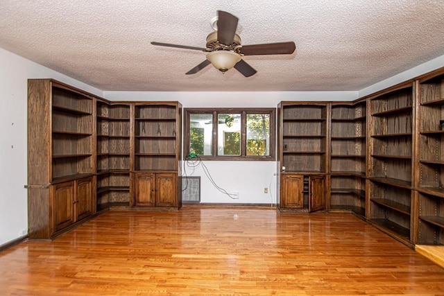 interior space featuring a textured ceiling, ceiling fan, baseboards, and light wood-style floors