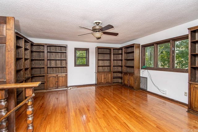 interior space featuring light wood-type flooring, baseboards, and a textured ceiling