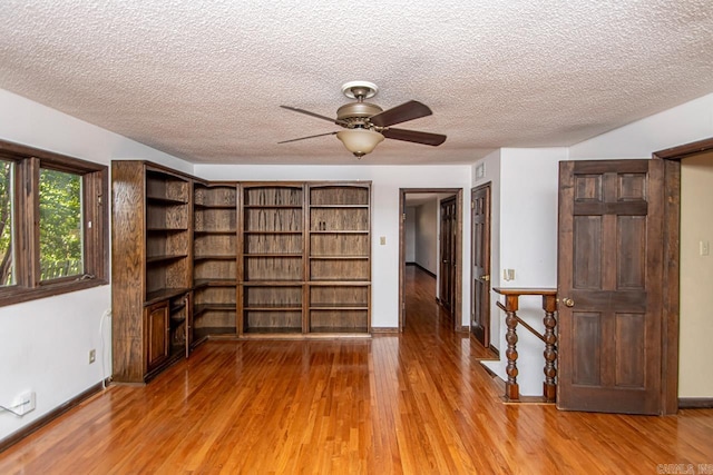 spare room with baseboards, visible vents, ceiling fan, wood finished floors, and a textured ceiling