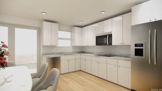 kitchen featuring light stone countertops, light wood-type flooring, sink, white cabinetry, and black appliances