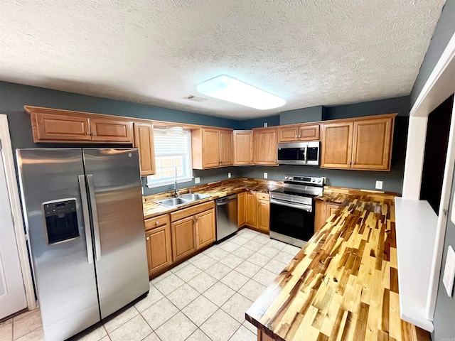 kitchen featuring light tile patterned floors, stainless steel appliances, a textured ceiling, and sink