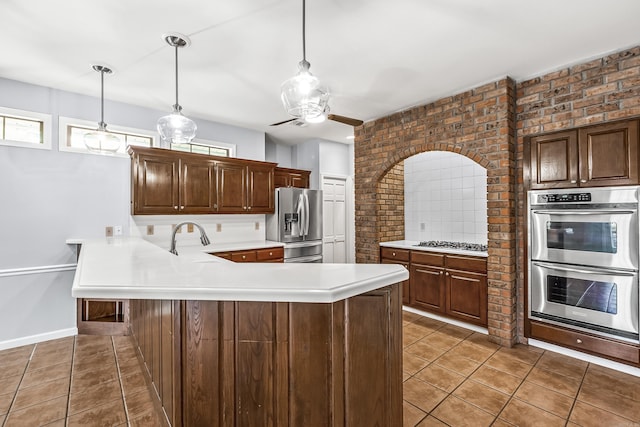 kitchen with hanging light fixtures, dark tile patterned floors, appliances with stainless steel finishes, and light countertops