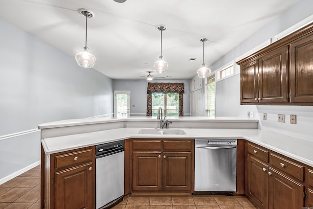 kitchen with decorative light fixtures, a peninsula, light countertops, stainless steel dishwasher, and a sink