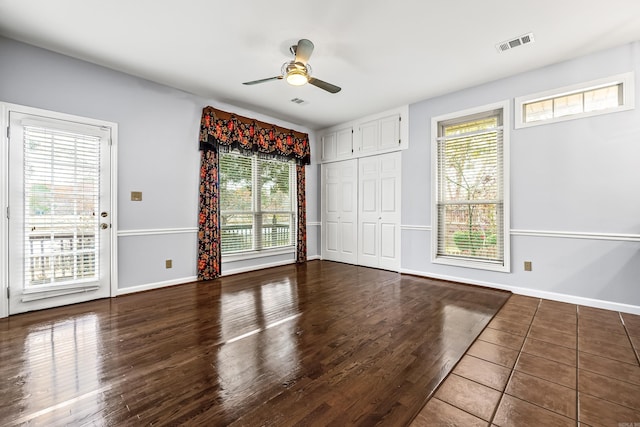 unfurnished room featuring plenty of natural light, visible vents, dark wood-style flooring, and baseboards