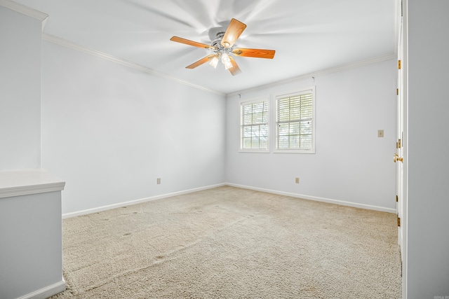 carpeted spare room with ceiling fan, ornamental molding, and baseboards