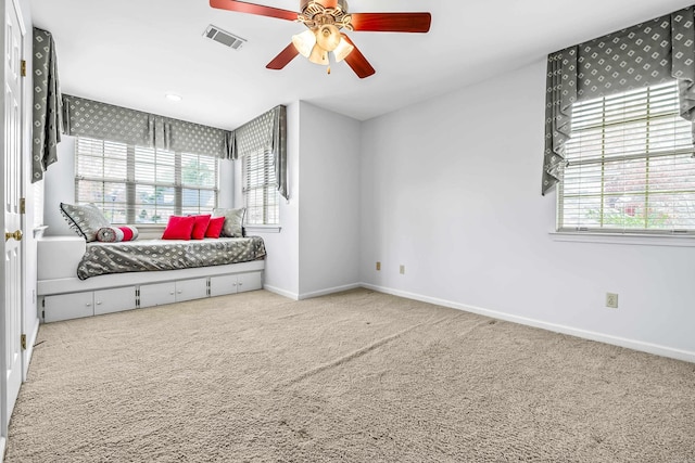 carpeted bedroom with a ceiling fan, visible vents, baseboards, and multiple windows