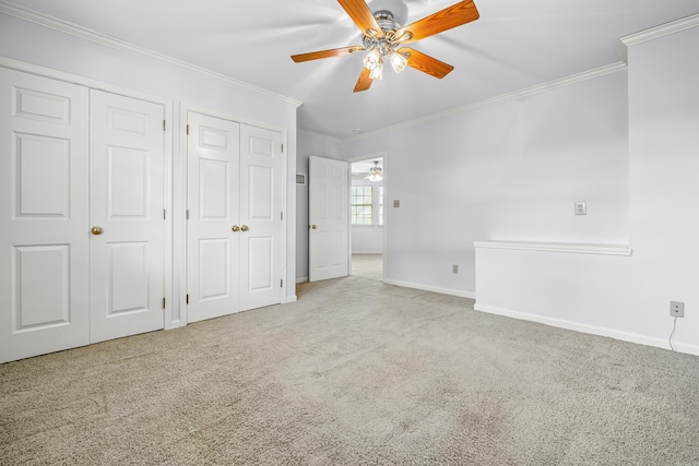 unfurnished bedroom with ornamental molding, light colored carpet, baseboards, and two closets