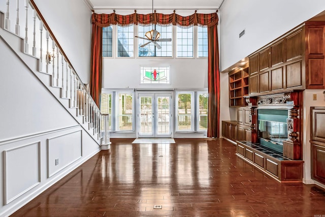 interior space featuring dark wood-type flooring, a fireplace, french doors, and a high ceiling