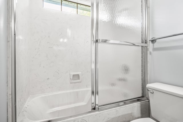 bathroom featuring combined bath / shower with glass door and toilet