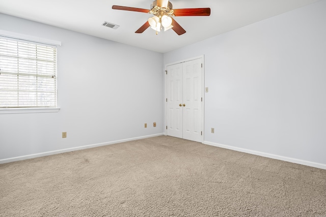 spare room with baseboards, visible vents, ceiling fan, and carpet flooring