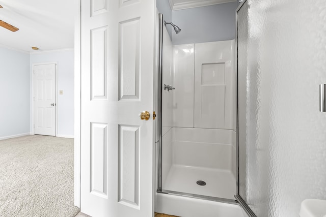 bathroom featuring a stall shower, crown molding, baseboards, and ceiling fan