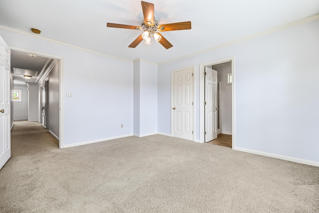 spare room featuring a ceiling fan, light colored carpet, crown molding, and baseboards