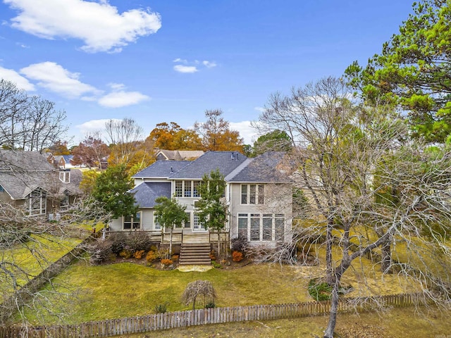 rear view of house with a lawn and fence