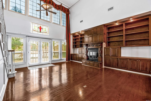 unfurnished living room with french doors, dark wood-type flooring, a glass covered fireplace, and visible vents