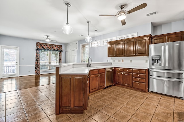 kitchen featuring stainless steel appliances, a peninsula, visible vents, hanging light fixtures, and light countertops