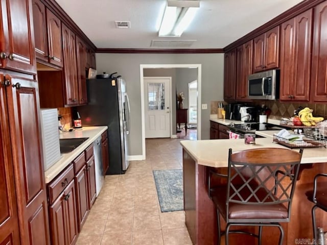 kitchen featuring tasteful backsplash, a kitchen breakfast bar, stainless steel appliances, ornamental molding, and light tile patterned floors