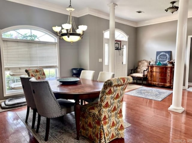 dining space with an inviting chandelier, decorative columns, crown molding, and hardwood / wood-style flooring