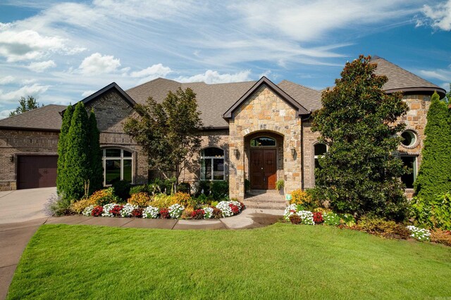 french country style house featuring a front yard and a garage