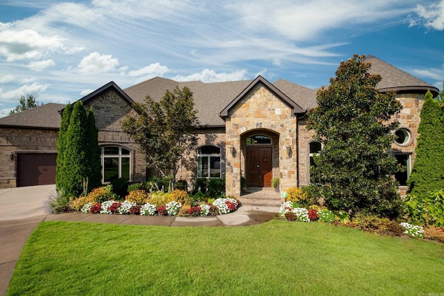 french country inspired facade featuring a garage and a front lawn