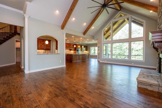 unfurnished living room featuring a stone fireplace, dark wood-type flooring, high vaulted ceiling, and beamed ceiling