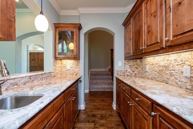 kitchen with sink, crown molding, light stone countertops, dark hardwood / wood-style flooring, and decorative light fixtures