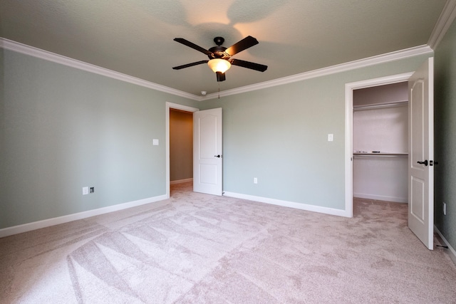 unfurnished bedroom featuring a walk in closet, ornamental molding, light colored carpet, and ceiling fan