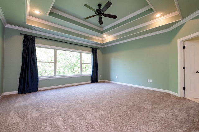 carpeted spare room with ceiling fan, ornamental molding, and a raised ceiling