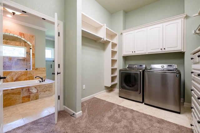 clothes washing area featuring cabinets, crown molding, washer and dryer, and light carpet