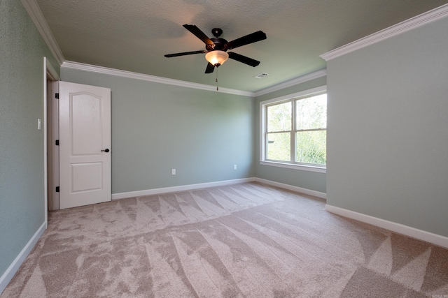 carpeted spare room featuring ceiling fan, ornamental molding, and a textured ceiling