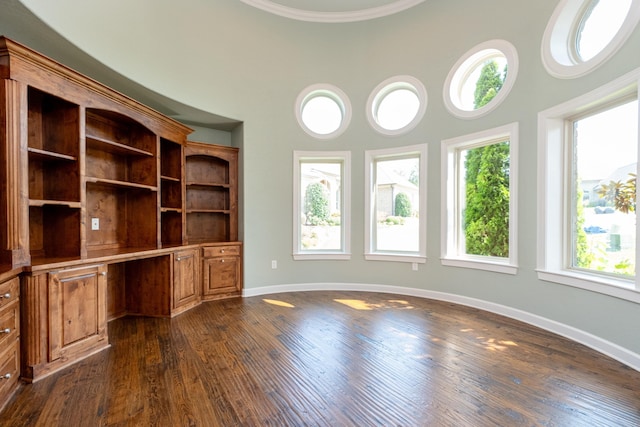 unfurnished office with dark wood-type flooring and built in desk