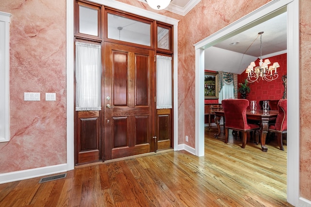 entrance foyer with a chandelier, ornamental molding, and hardwood / wood-style floors