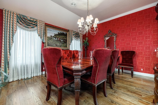 dining room featuring wood-type flooring, ornamental molding, a healthy amount of sunlight, and an inviting chandelier