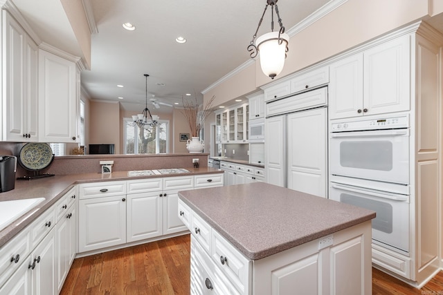 kitchen featuring crown molding, pendant lighting, light hardwood / wood-style floors, and built in appliances