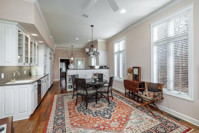 dining area with ceiling fan with notable chandelier, crown molding, dark hardwood / wood-style flooring, and sink