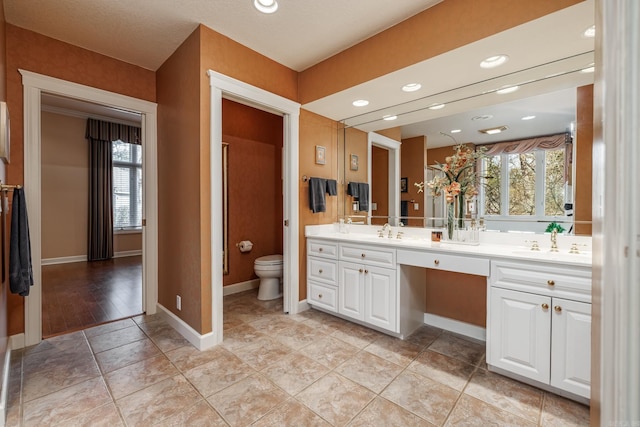 bathroom with dual bowl vanity, tile patterned flooring, and toilet