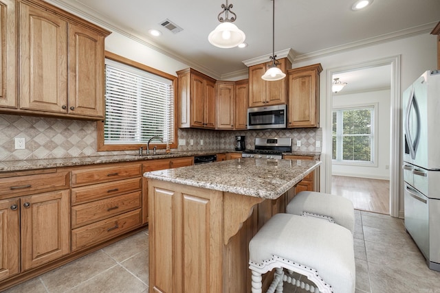 kitchen featuring appliances with stainless steel finishes, hanging light fixtures, light stone countertops, tasteful backsplash, and a kitchen island