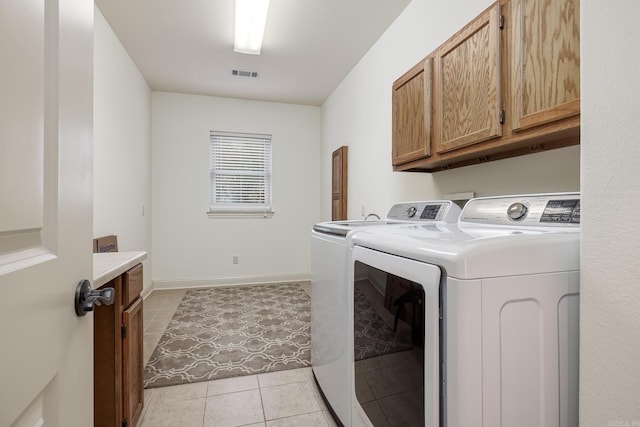 washroom with independent washer and dryer, light tile patterned floors, and cabinets