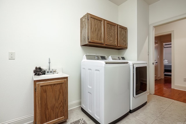 laundry area with cabinets, light tile patterned floors, and washer and clothes dryer