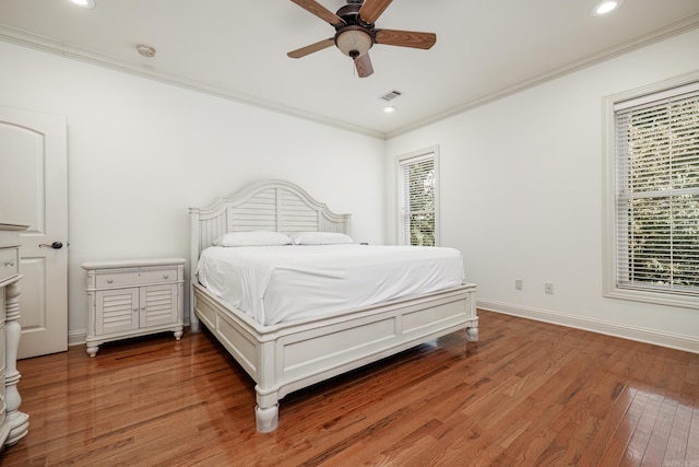 bedroom with ornamental molding, hardwood / wood-style floors, ceiling fan, and multiple windows