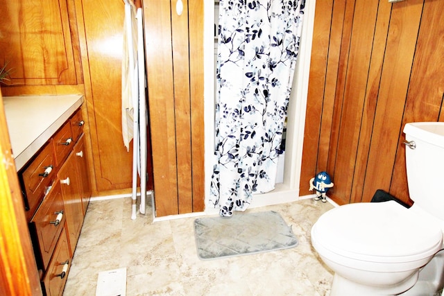 bathroom featuring vanity, wood walls, toilet, and tile patterned flooring