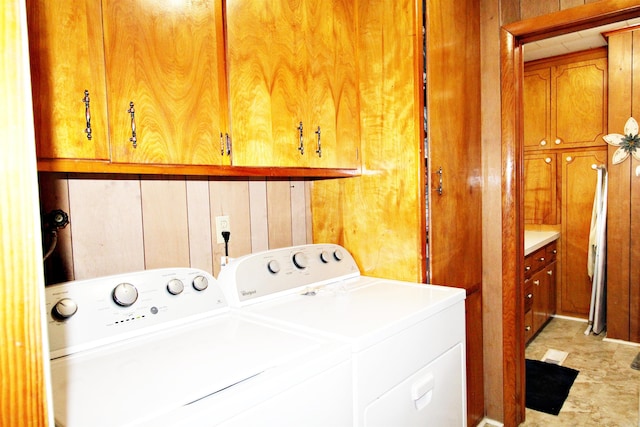 washroom featuring wood walls, cabinets, light tile patterned floors, and washer and dryer