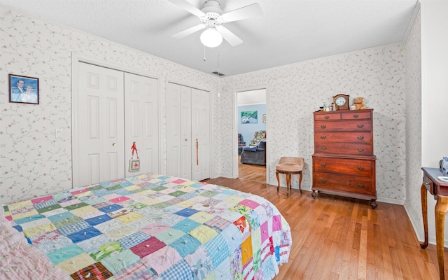 bedroom featuring two closets, ceiling fan, and light wood-type flooring