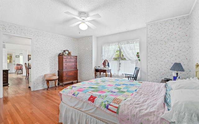 bedroom featuring ceiling fan, hardwood / wood-style floors, and a textured ceiling