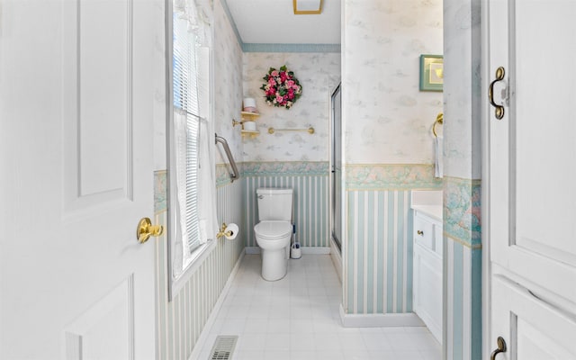 bathroom featuring a shower with door and toilet