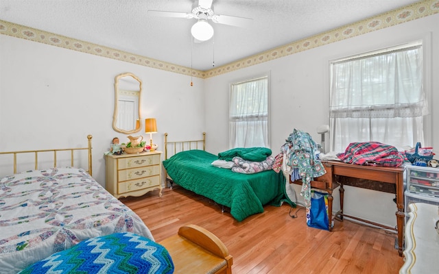 bedroom featuring ceiling fan, hardwood / wood-style flooring, and a textured ceiling