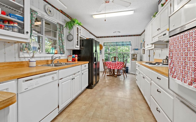 kitchen with sink, white appliances, a textured ceiling, ceiling fan, and white cabinets