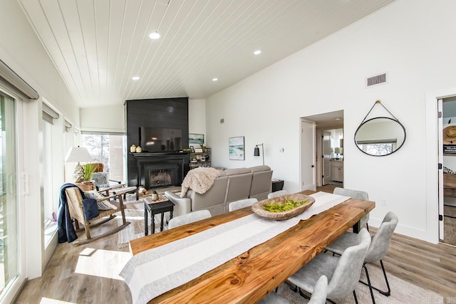 dining space with a fireplace, lofted ceiling, and light hardwood / wood-style floors