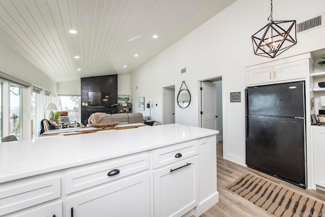 kitchen featuring lofted ceiling, light wood-type flooring, white cabinetry, wooden ceiling, and black refrigerator