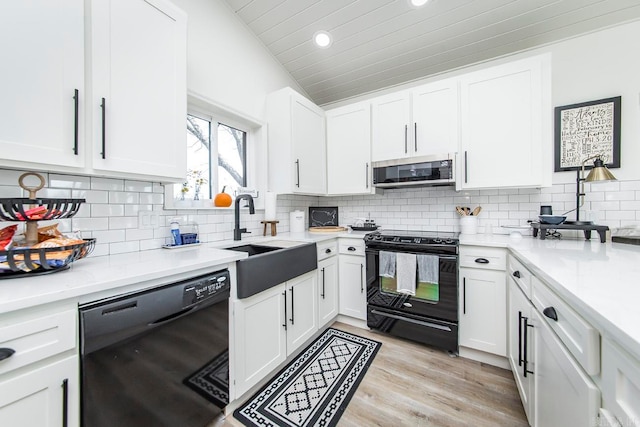 kitchen featuring backsplash, vaulted ceiling, black appliances, and light hardwood / wood-style floors