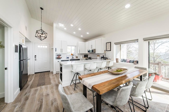 dining room with light wood-type flooring, wood ceiling, and vaulted ceiling